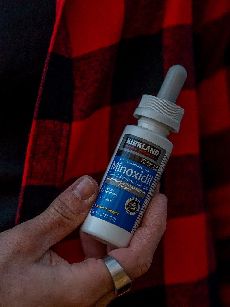 Frasco de Minoxidil Kirkland sendo segurado, produto importado original para barba e cabelo
